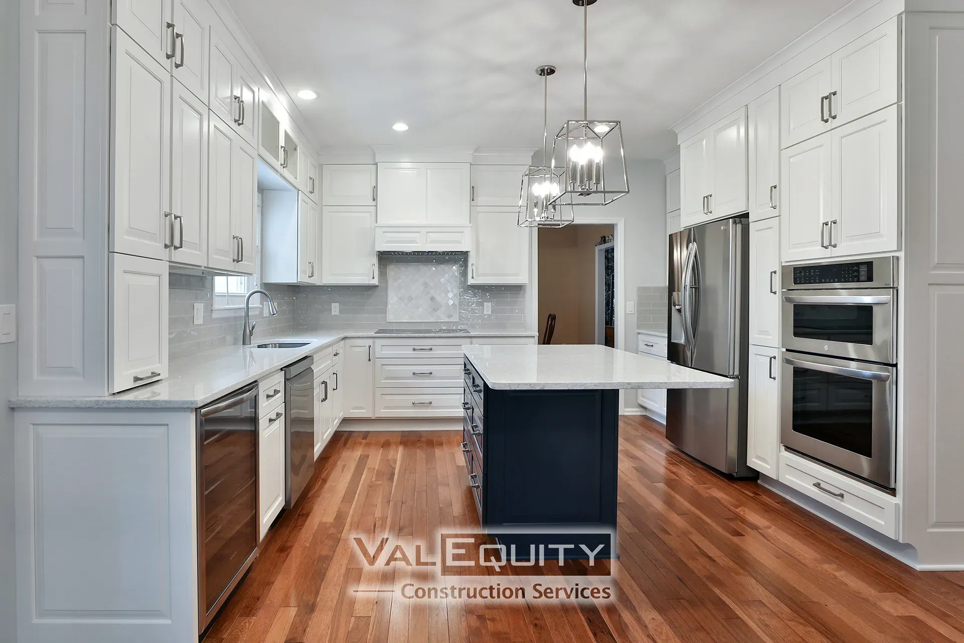Modern kitchen with white cabinets, stainless steel appliances, and hardwood floors.